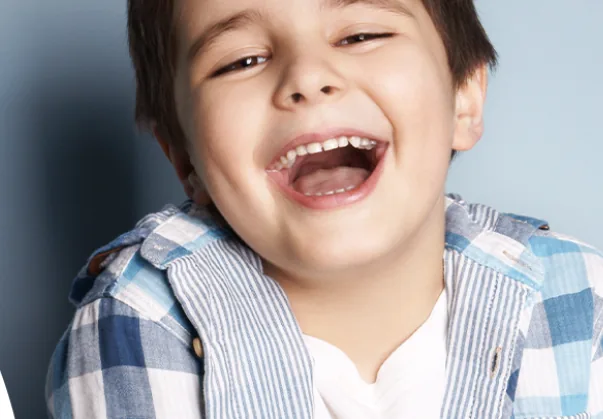 A boy laughing with his milk teeth showing